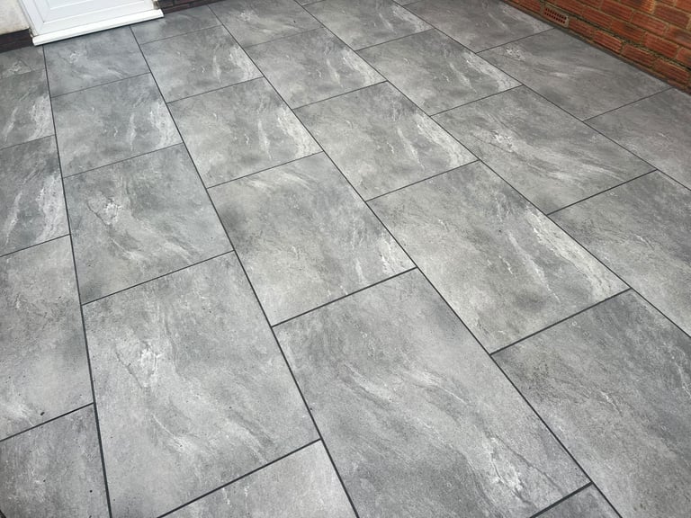 Grey porcelain patio laid by PC Landscaping at a South Devon home, with tight joints and a level finish
