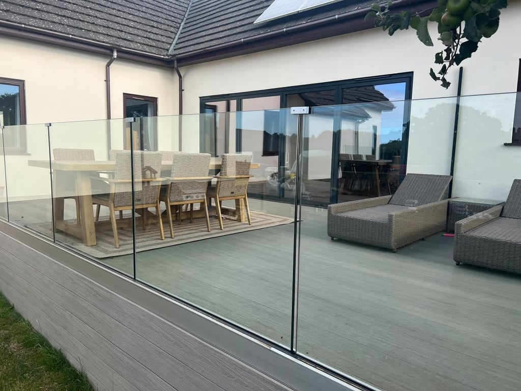 Grey composite decking with glass balustrade and outdoor dining area built by PC Landscaping in South Devon